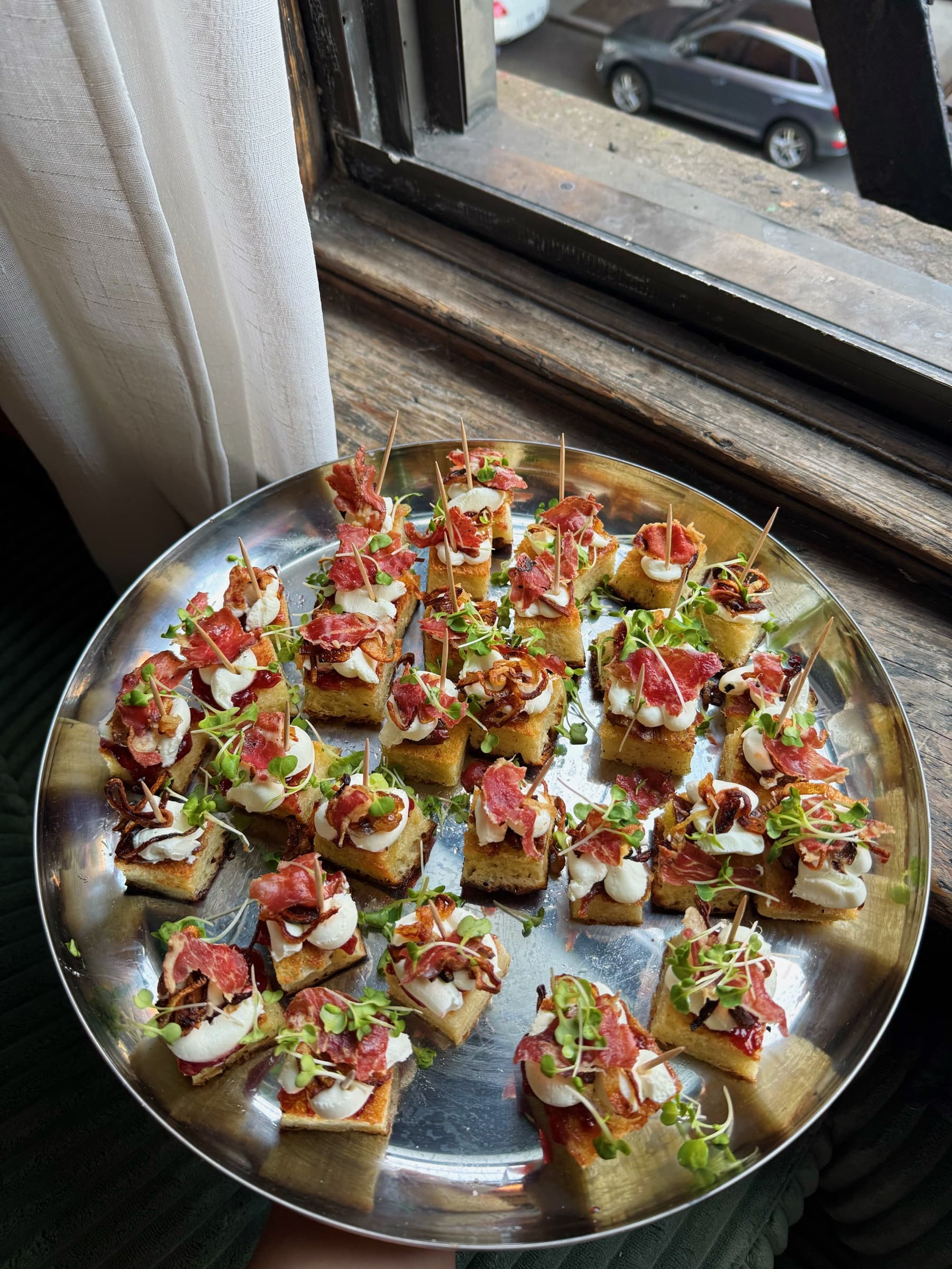 Bites arranged on a silver tray by a window